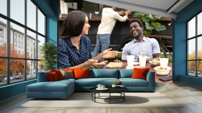 Happy multiracial friends having fun eating in a street food truck market Wall mural