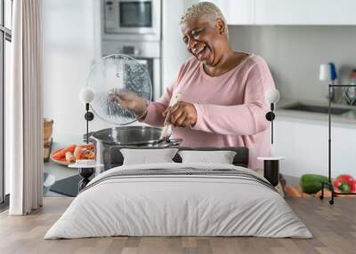 Happy senior woman having fun preparing lunch in modern kitchen - Hispanic Mother cooking for the family at home Wall mural