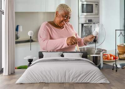 Happy senior woman preparing lunch in modern kitchen - Hispanic Mother cooking for the family at home Wall mural