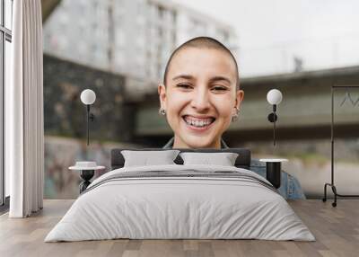 Happy young woman with shaved head smiling in front of camera Wall mural