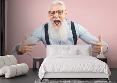 Senior man having fun posing in front camera - Happy mature male enjoying retired time - Elderly people lifestyle and hipster culture concept - Pink background Wall mural