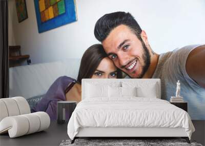 Stunning happy couple taking a selfie while relaxing at home - Boyfriend and girlfriend taking a selfie on a white sofa in their apartment Wall mural