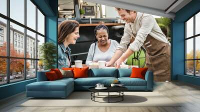 Young Food truck owner serving meal to customers table - Happy multiracial females having fun lunching together Wall mural