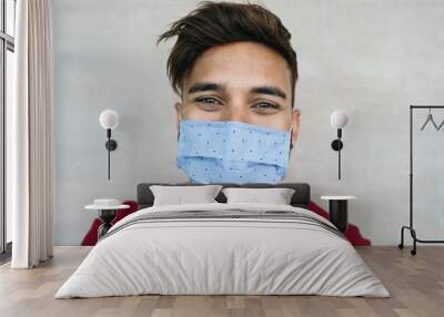 Young man wearing face mask portrait - Latin boy using protective facemask for preventing spread of corona virus - Health care and youth millennial people concept Wall mural