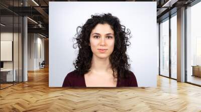 Attractive young brown haired woman looking at camera. Portrait of caucasian curly haired female. Isolated on white background. Wall mural