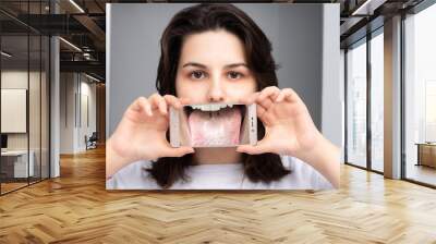 Girl showing the magnified image of her tongue with Candida albicans through a smart phone Wall mural