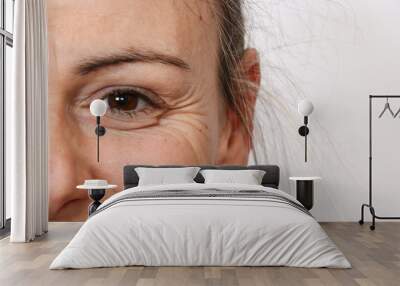 Half face closeup studio portrait showing eye wrinkles and crow's feet on a smiling female face. Happy aging skincare concept Wall mural