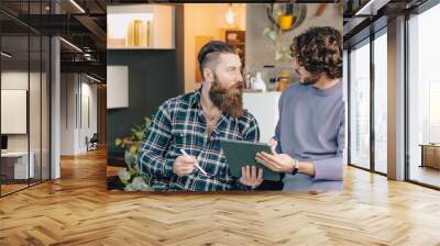 Two male designers discussing about a project using a digital tablet in their office Wall mural