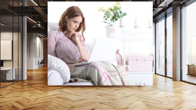 Beautiful young girl sitting in a chair with a laptop Wall mural