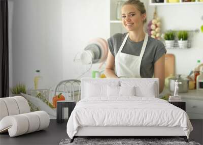 Beautiful young woman making salad at home Wall mural