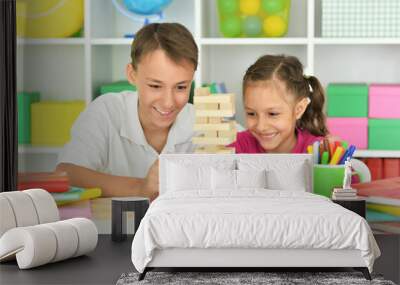 Brother and sister playing with wooden blocks at playroom Wall mural