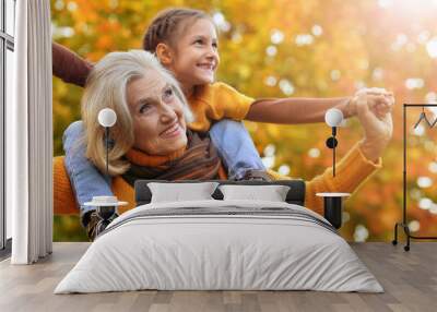 Grandmother and granddaughter play together in autumn Wall mural