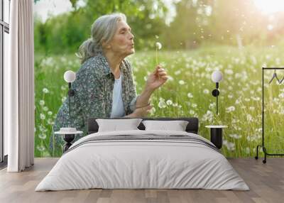 old woman in a field with dandelions in summer Wall mural