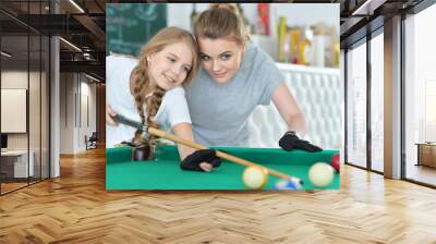 Portrait of cute girl with mother playing billiard Wall mural