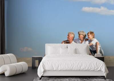 Portrait of grandparents with their grandchildren on the sand Wall mural