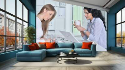 Portrait of two young women working at office with laptop Wall mural