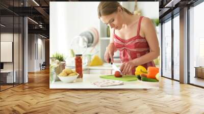 Portrait of young woman cooking in kitchen Wall mural