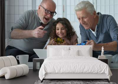 Two old men with granddaughter playing on laptop  Wall mural