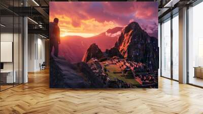 A hiker stands at sunrise above the ancient ruins of Machu Picchu, surrounded by majestic mountains and vibrant colors of dawn. Wall mural