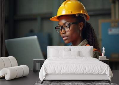 African american woman engineer focused on digital data while wearing safety gear in industrial workspace during the day Wall mural