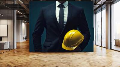 A man in a suit holds a yellow helmet. He poses for a photo. Concept of confidence and professionalism. Wall mural