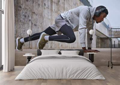 Athletic man is exercising near the grey wall Wall mural