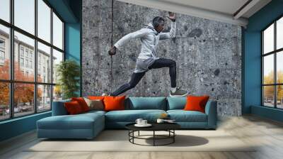 Athletic man is running near the grey wall Wall mural