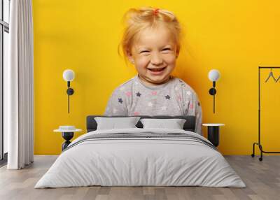 Child in pajamas makes faces on yellow background Wall mural