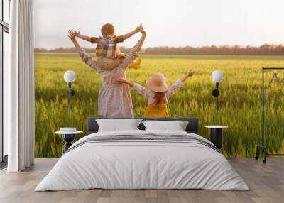 Happy family, mom, son and girl in straw hat in wheat field at sunset.  The concept of organic farming and healthy lifestyle, healthy food, happiness and joy Wall mural