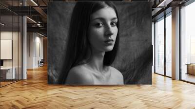 Dramatic black and white portrait of a beautiful lonely girl with freckles isolated on a dark background in studio shot Wall mural