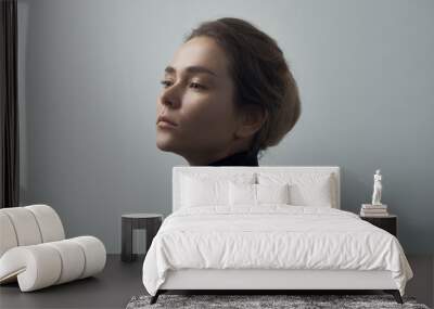 Dramatic portrait of a young beautiful girl with freckles in a black turtleneck on white background in studio Wall mural