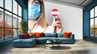 female doctor holding a stethoscope on a light background. Added flag of Austria. Concept medicine, level of medicine, virus, epidemic Wall mural