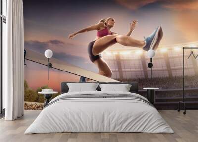 Female Track and field athlete jumps over the barrier at the running track in professional stadium Wall mural