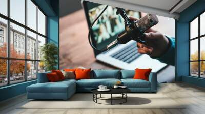 A man host streaming his audio podcast using microphone and laptop at his small broadcast studio, close-up Wall mural