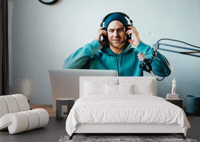 Cheerful host streaming his audio podcast at small and cozy home broadcast studio Wall mural