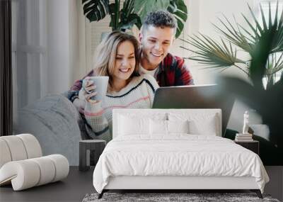 Couple in love at home. Young family watching TV series using laptop and sitting on the couch Wall mural