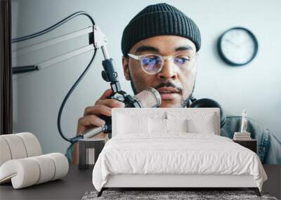 Mixed race host streaming his audio podcast at small and cozy home broadcast studio Wall mural