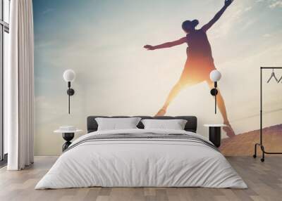 Silhouette of pretty woman jumping near ocean. Spending good time and fun. Intentional sun glare and lens flare effect, vintage color Wall mural