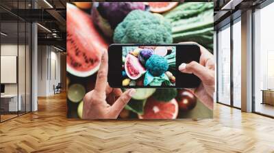 Table with a lot of delicious meals and plates. Fruits and vegetables. Woman's hands with cell phone taking food photo Wall mural