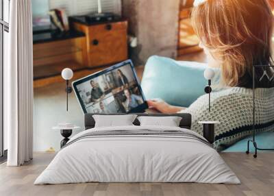 Woman browsing network on laptop and siting on couch Wall mural