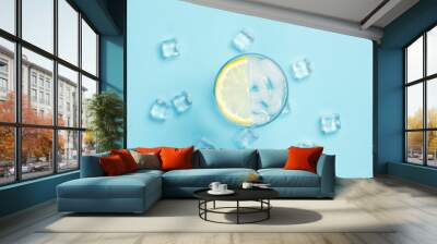 Glass of water or drink with ice and lemon on a blue background with ice cubes. Concept of a hot summer, alcohol, cooling drink, quenching thirst. Flat lay, top view Wall mural