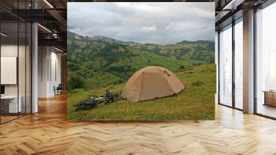 Green tent and two bicycles on a background of mountains Wall mural