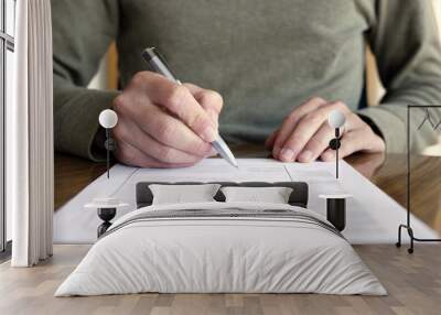 man writing on paper with pen on table Wall mural