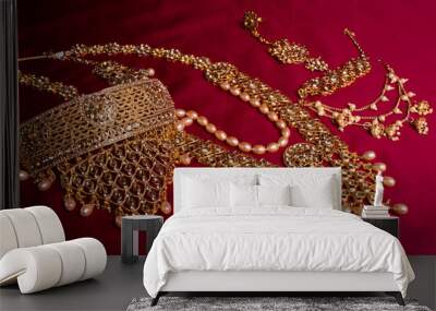 Indian traditional gold Indian wedding women's jewelry on red saree background. Close-up. Still-life. Wall mural