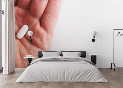 A man holds a white pill in the palm of his hand, close-up Wall mural