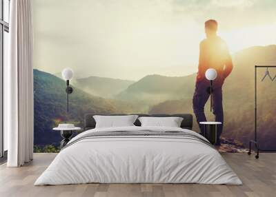 traveler young man standing in summer mountains at sunset and enjoying view of nature Wall mural