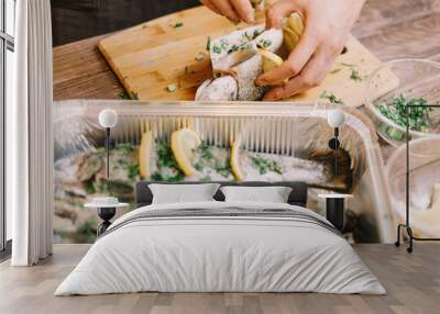 Woman preparing raw fish with lemons and greenery. Wall mural