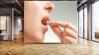 Woman taking a medical capsule or vitamin. Wall mural