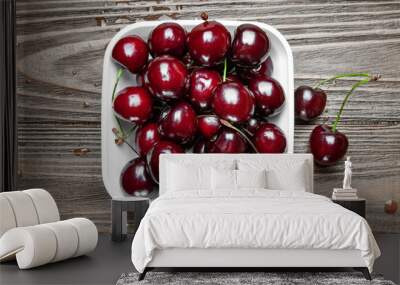 Top view of fresh ripe juicy sweet cherries in a white plate on a wooden background. Wet sweet cherries with water drops. Close-up of many cherries. Wall mural