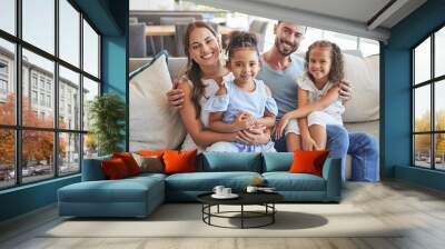 Father, mother and children smile, love and relax on the sofa together in the house living room. Portrait of happy family bonding in a lounge with happiness, care and trust in a healthy relationship Wall mural